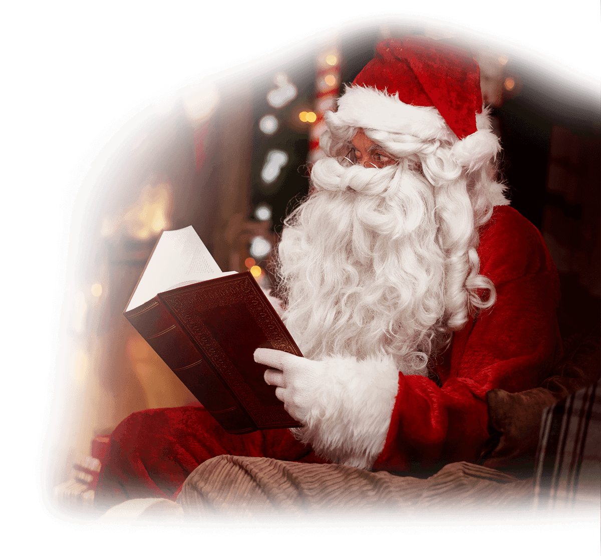Father Christmas, in his traditional red suit and hat, sits indoors at Jingle Bell Junction reading a large book. Warm lights and festive decorations softly blur in the background, creating a cosy holiday atmosphere.